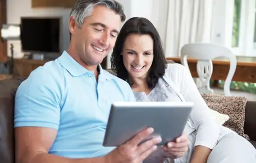 Couple sitting on sofa making an online purchase on a tablet